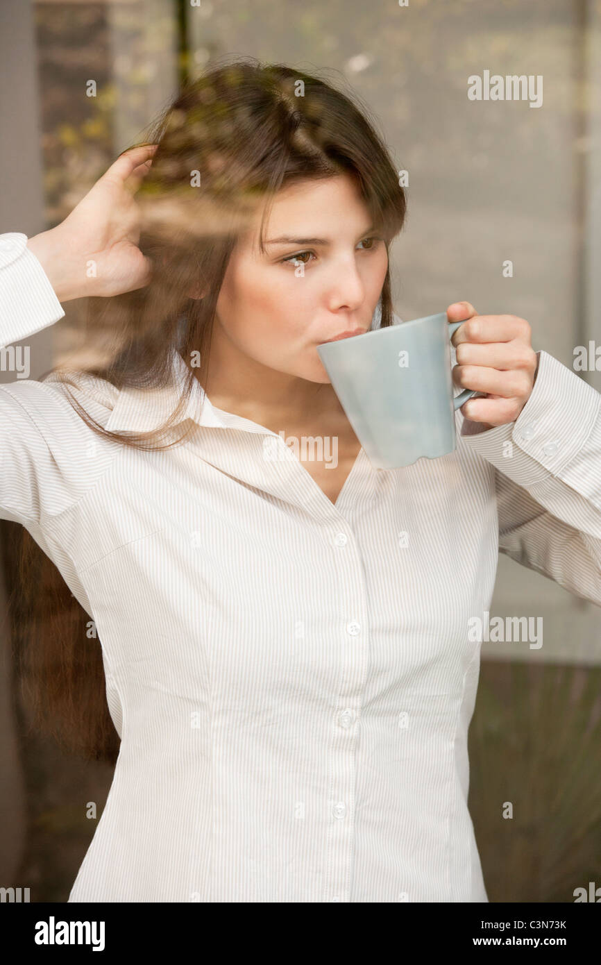 Femme d'une balle dans une fenêtre de boire du thé Banque D'Images