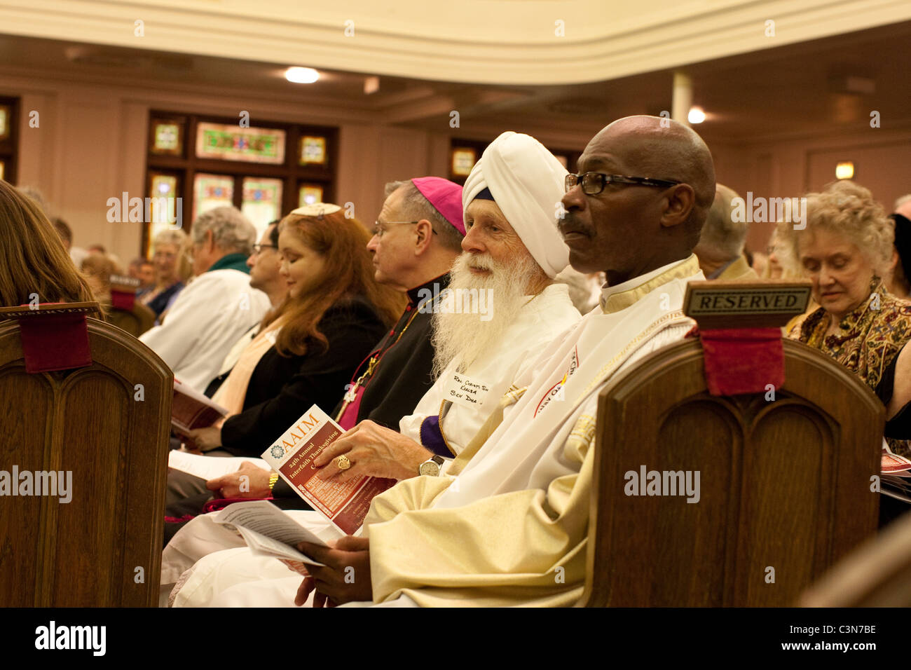 Les chefs religieux de différentes confessions et origines ethniques et nationalités s'asseoir ensemble dans un banc à une église méthodiste Banque D'Images