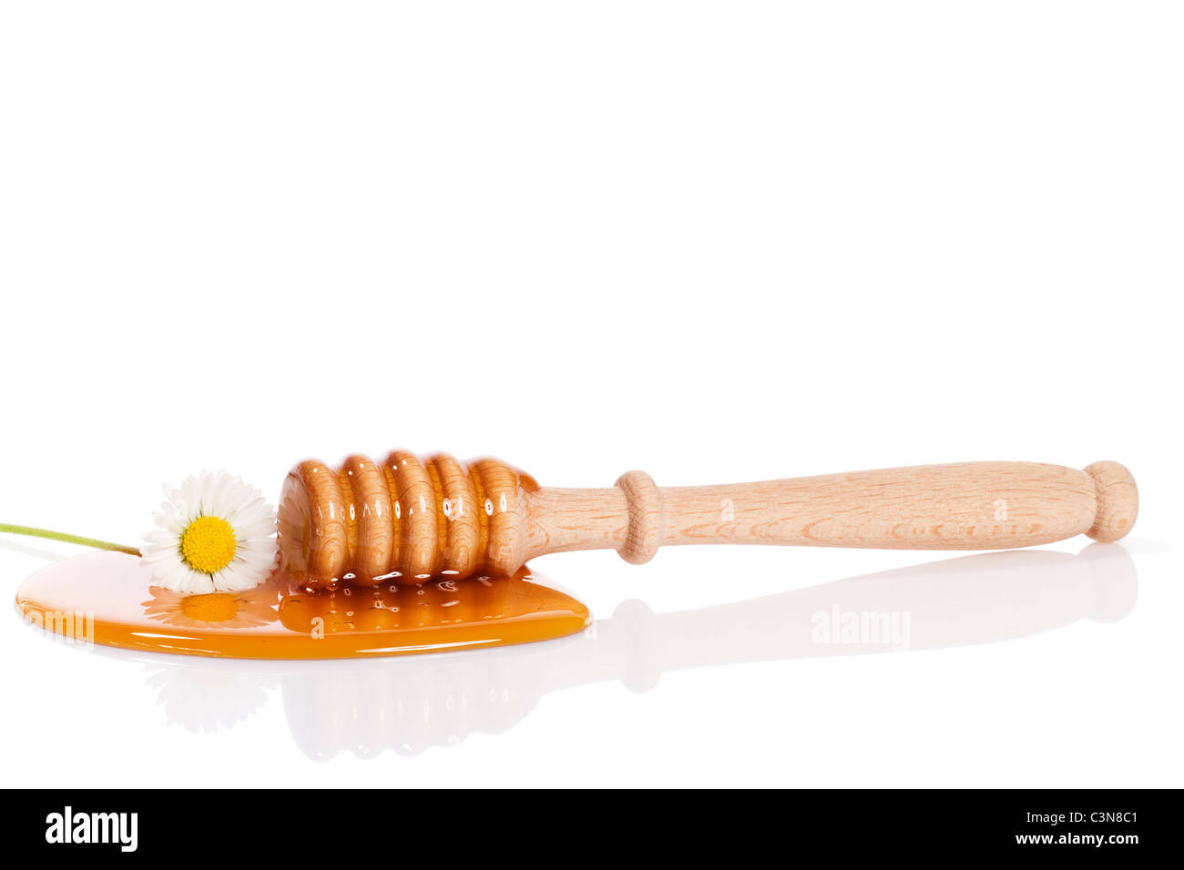Balancier et d'une guirlande de miel dans une flaque de miel sur fond blanc Banque D'Images
