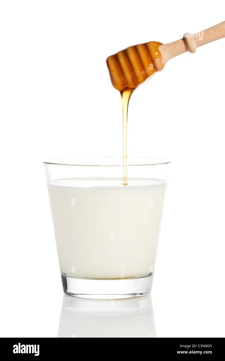 Le miel la chute d'un balancier de miel dans un verre de lait sur fond blanc Banque D'Images