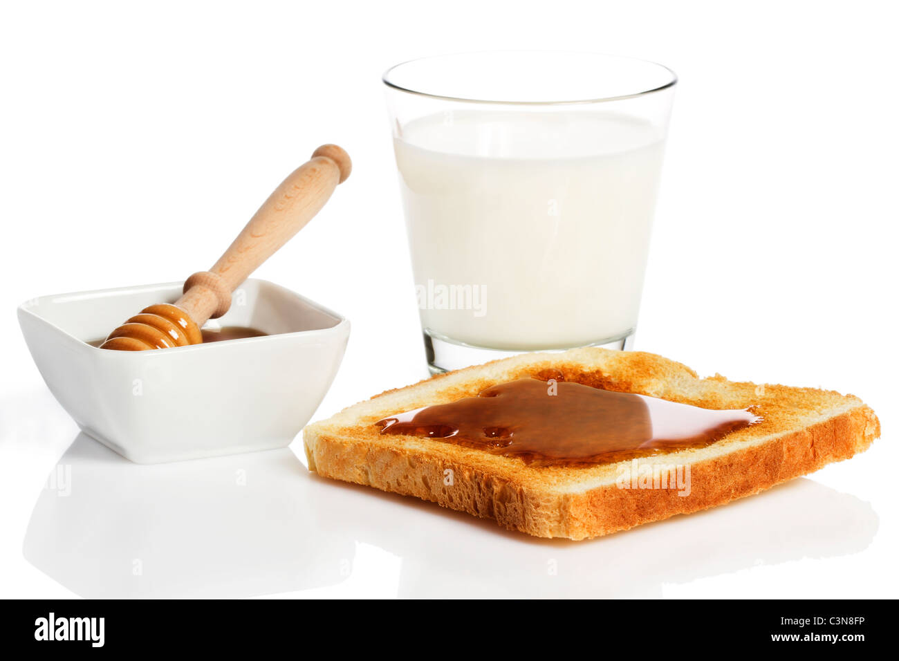 Pain grillé avec du miel, un verre de lait et miel un balancier dans un pot avec du miel sur fond blanc Banque D'Images