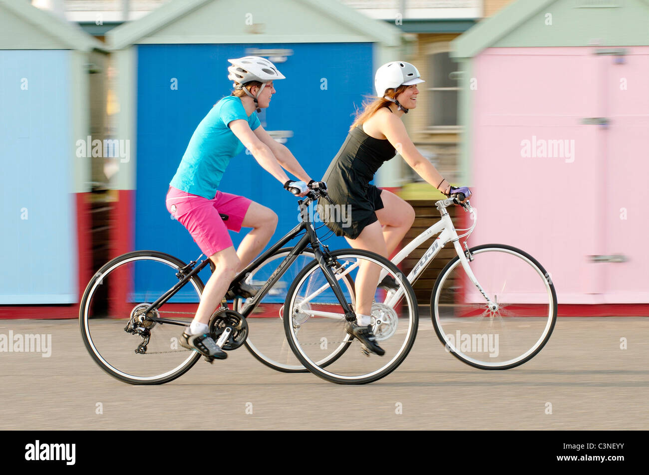 Les femmes équitation leurs bicyclettes passé plage couleur hits. Front de mer de Brighton, Brighton, UK Banque D'Images