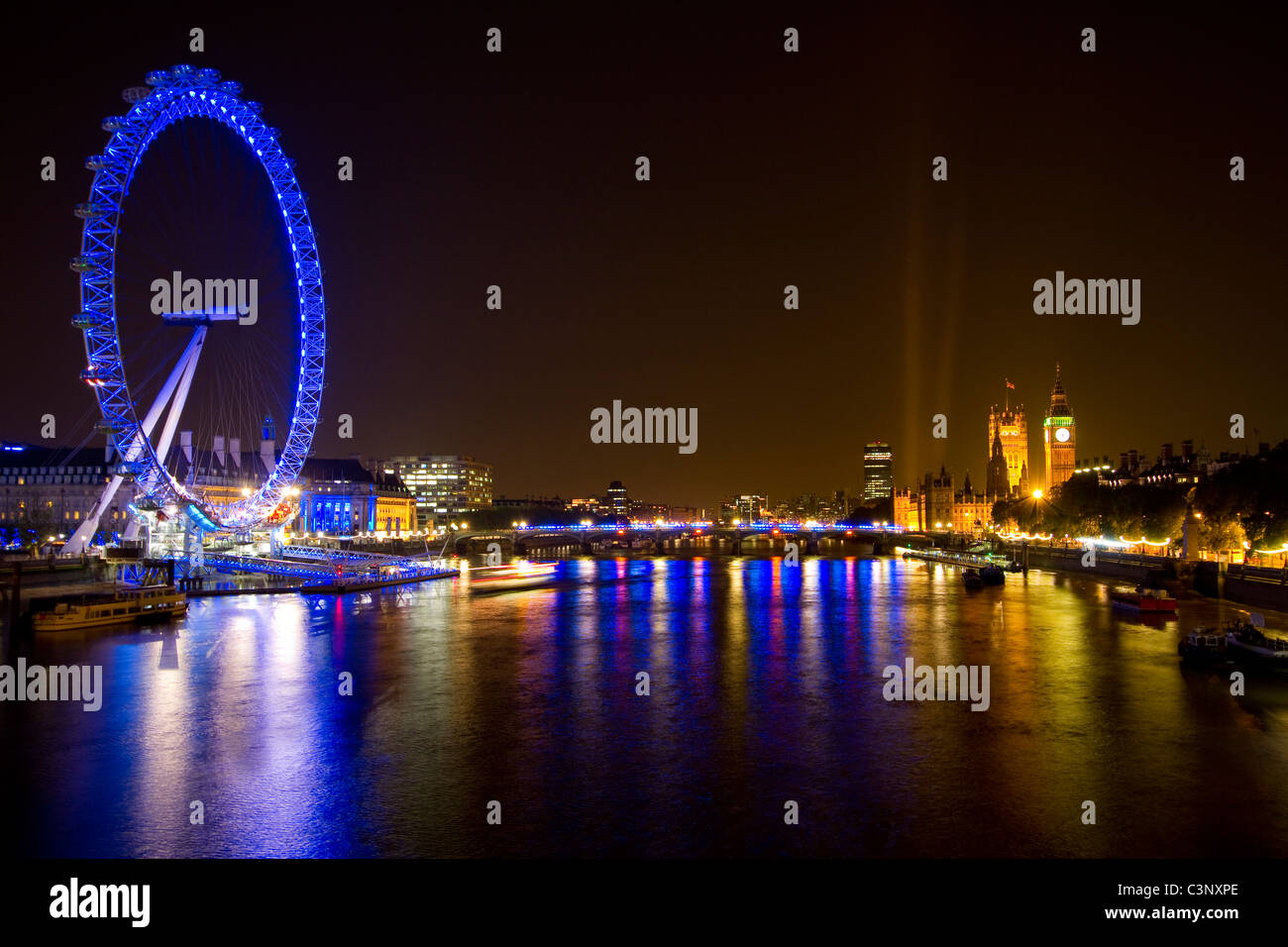 Nuit à Londres. Des lumières de Westminster et le London Eye refléter sur la Tamise Banque D'Images