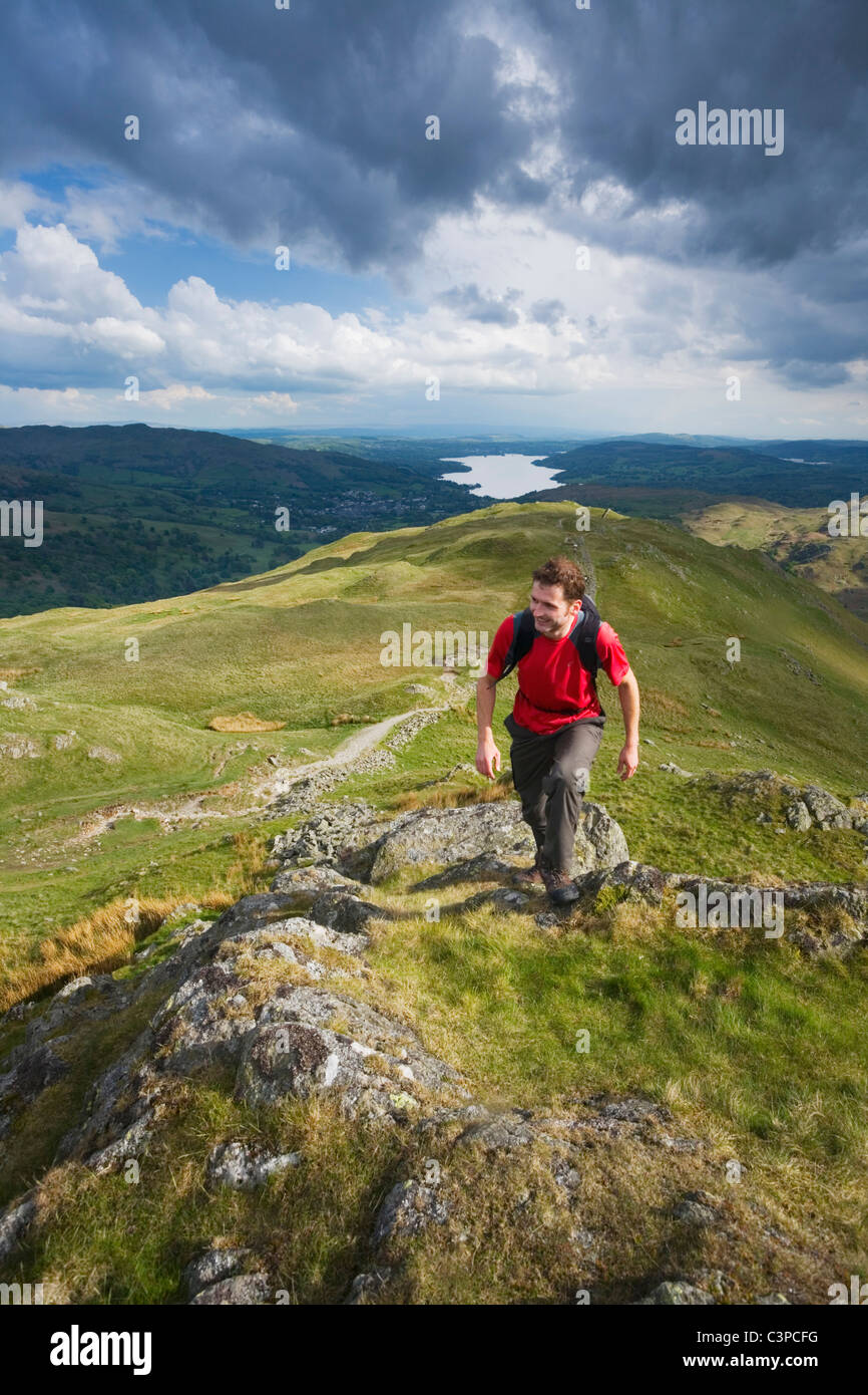 Homme de race blanche à monter avec Pike Heron Windermere dans la distance. Parc National de Lake District. La région de Cumbria. L'Angleterre. UK. Banque D'Images