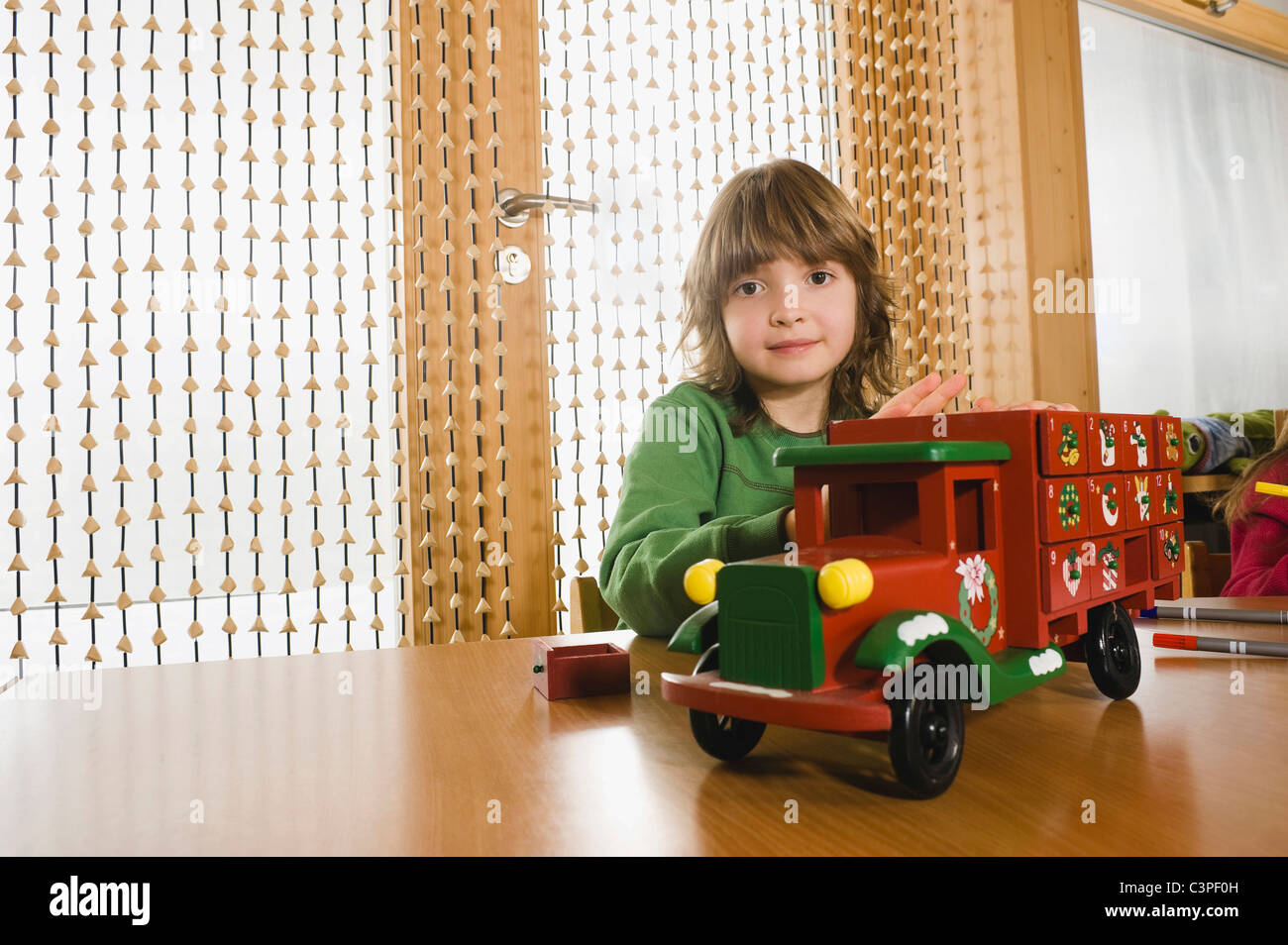 Allemagne, Boy (6-7) dans les jardins d'Playing with toy voiture, portrait Banque D'Images