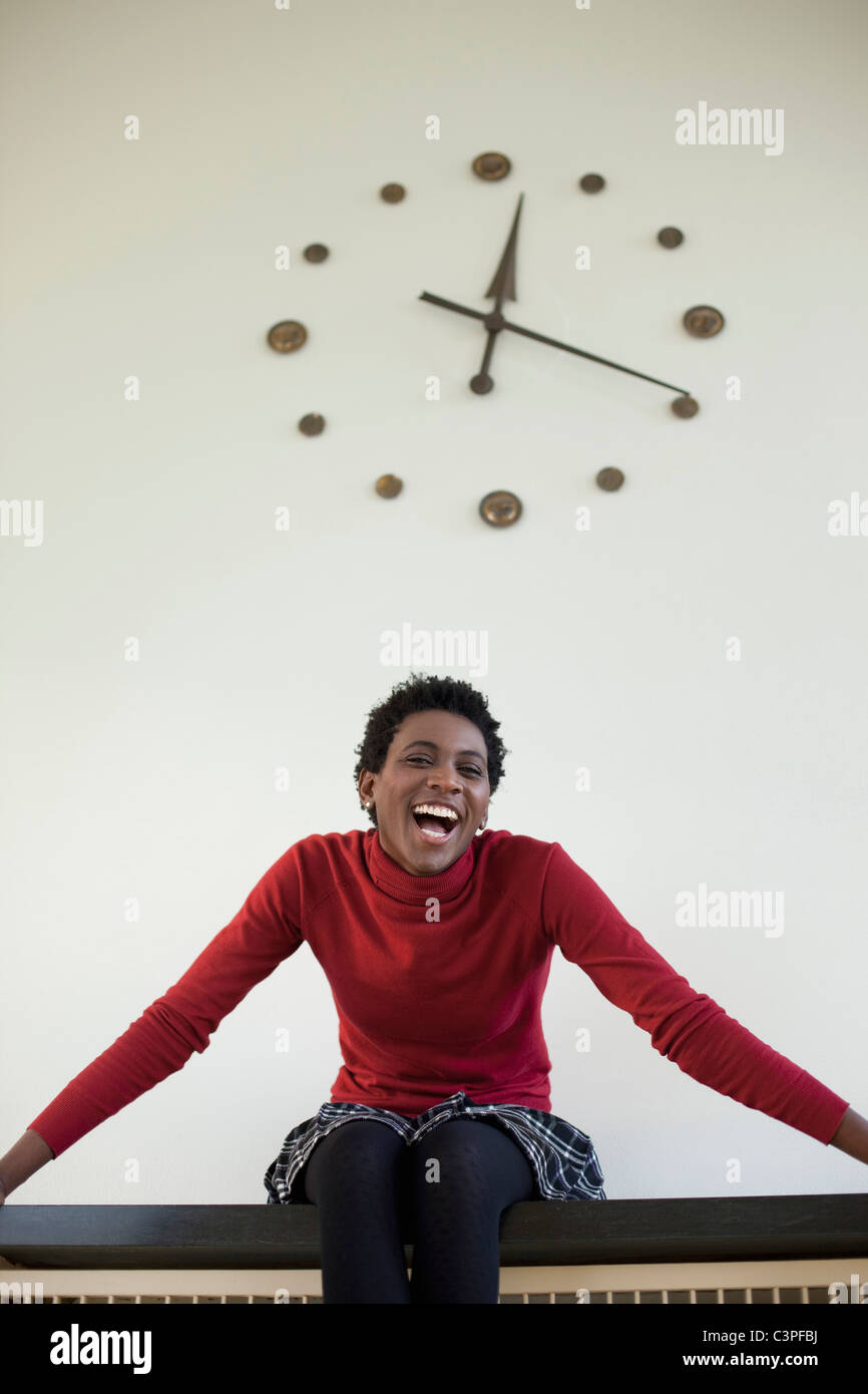 L'Allemagne, Leipzig, university student sitting against wall clock Banque D'Images