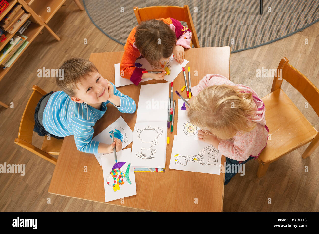 L'Allemagne, les enfants dans les jardins d'assis à table des dessins, elevated view Banque D'Images
