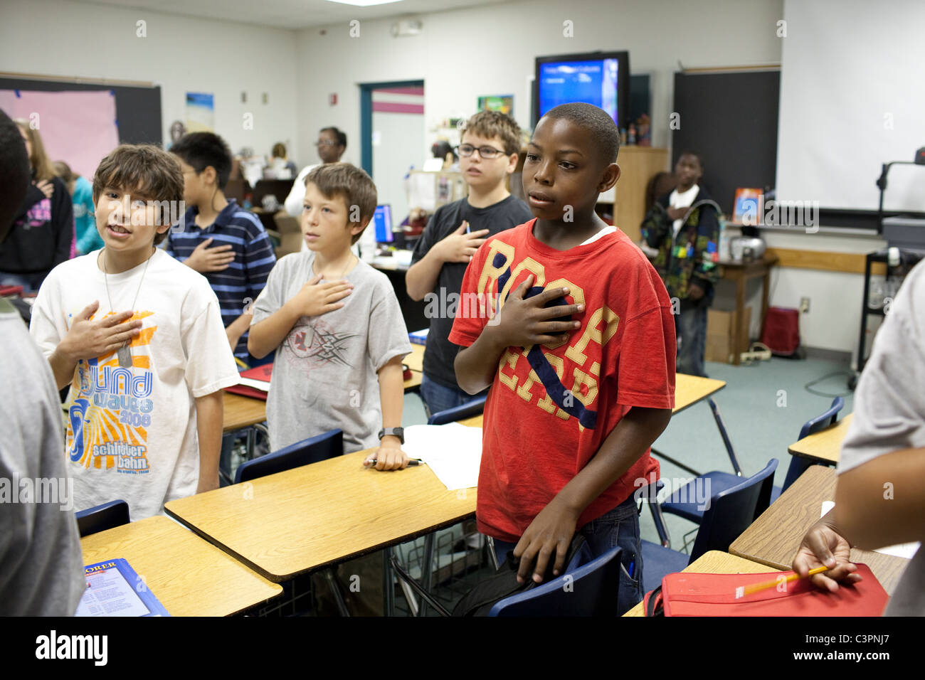 Les élèves de l'école intermédiaire stand à début de classe avec la main sur le coeur de réciter le serment d'allégeance Banque D'Images