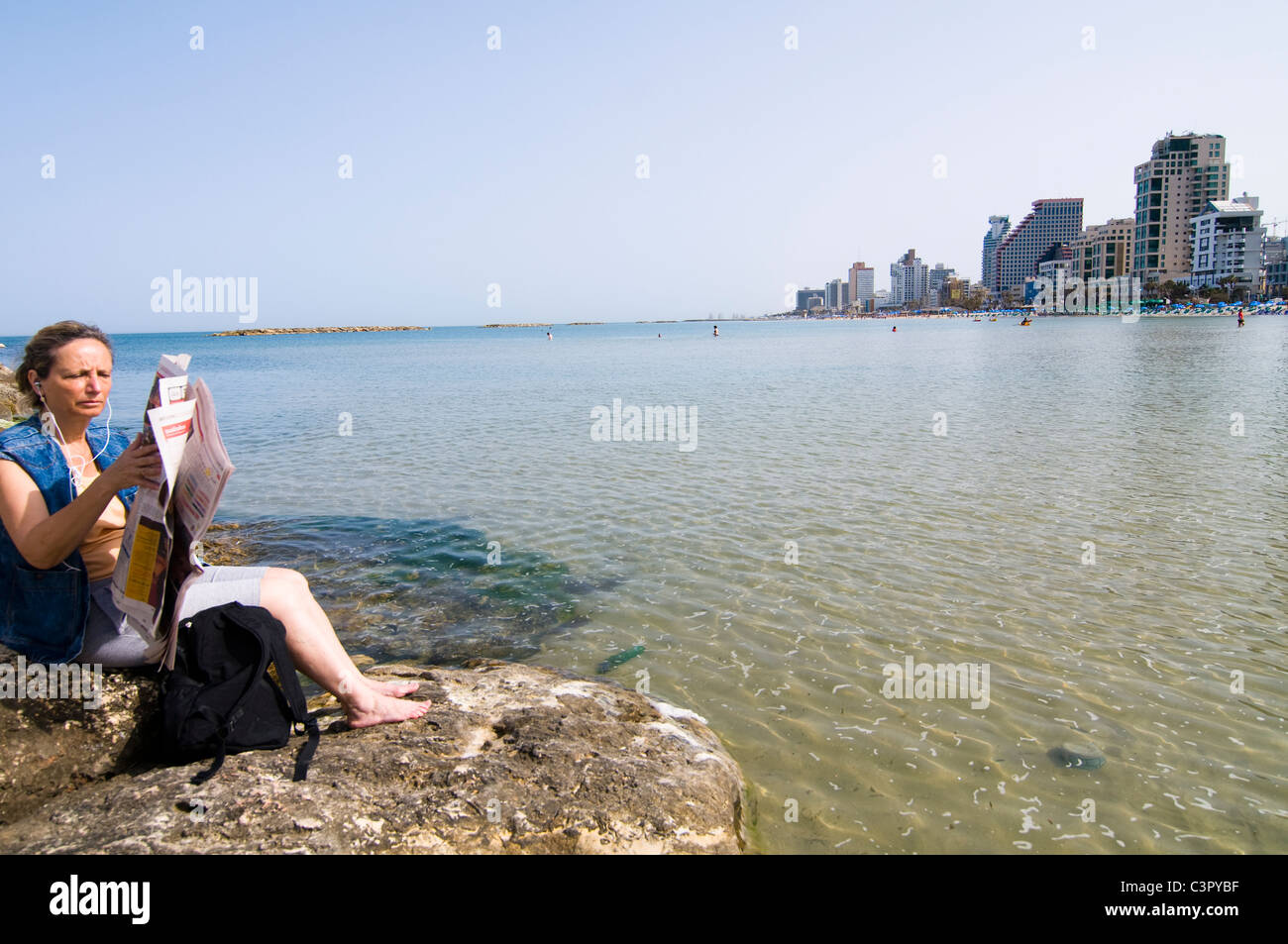 Se détendre et lire le journal du jour sur la plage de Tel-Aviv. Banque D'Images
