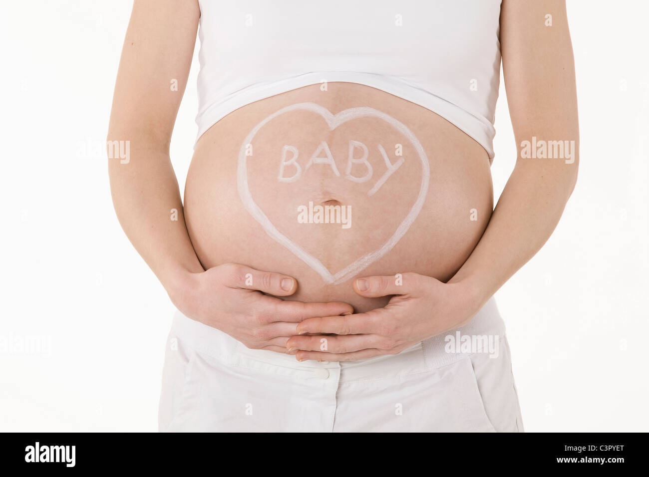 Forme de coeur dessiné sur le ventre de femme enceinte, mid section Banque D'Images
