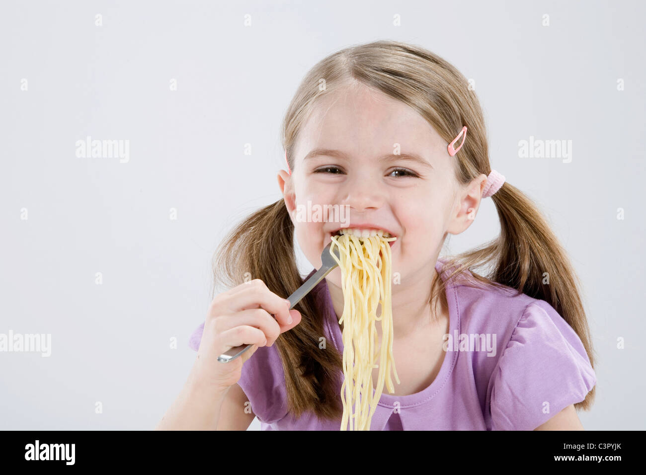 Girl (4-5) eating spaghetti, smiling, portrait Banque D'Images