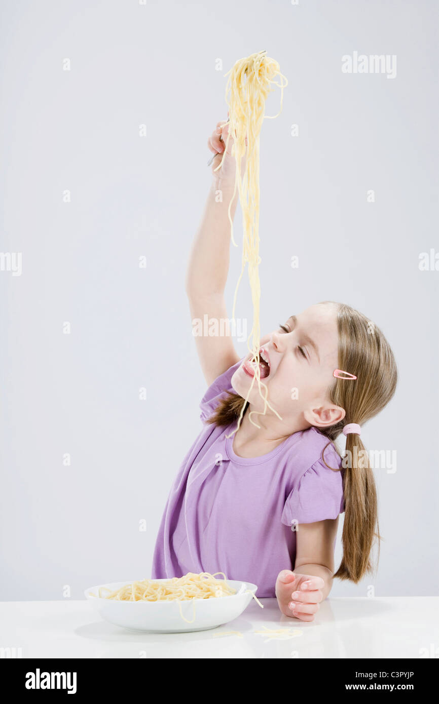 Girl (4-5) eating spaghetti, les yeux fermés Banque D'Images