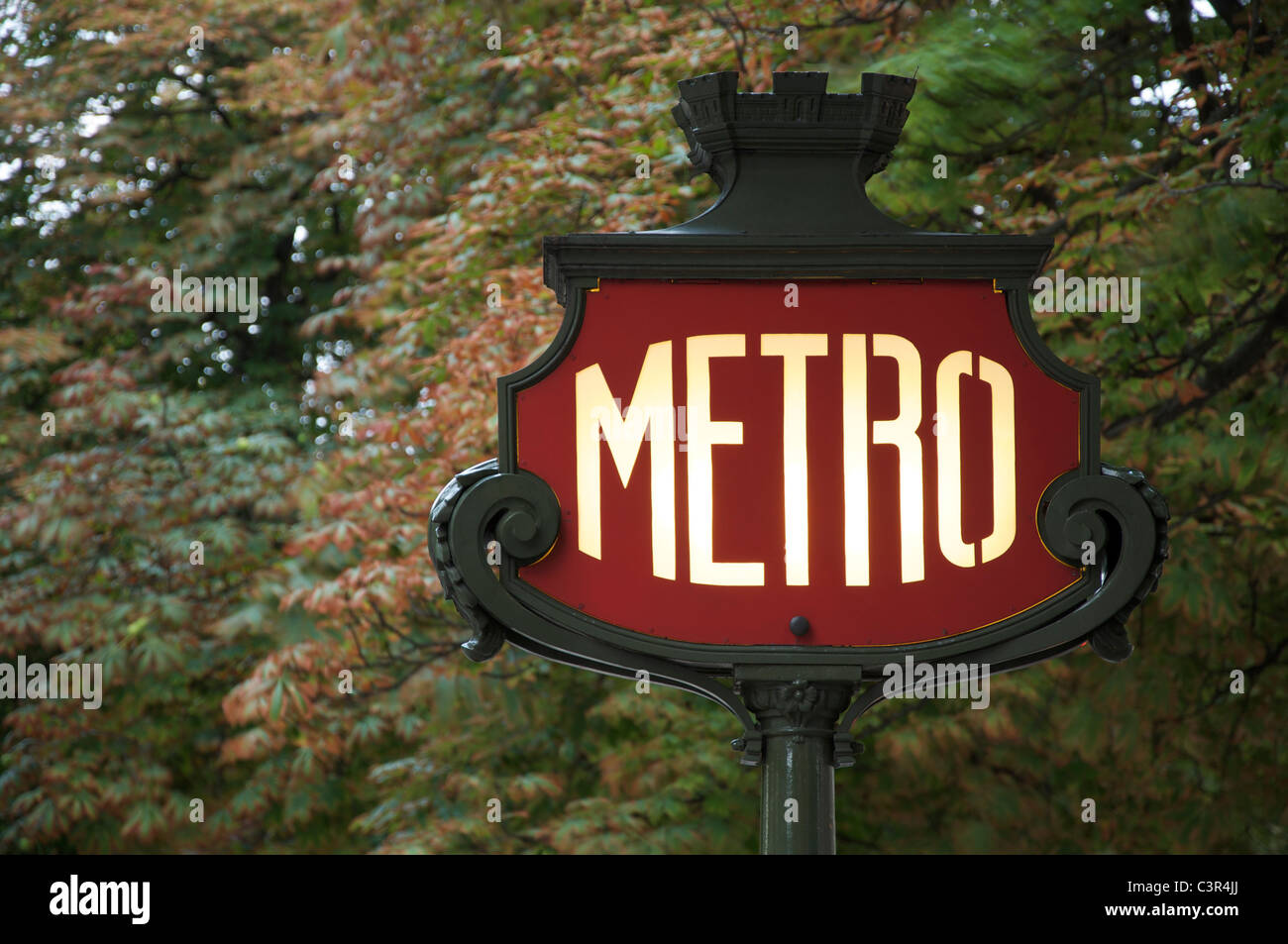 Un emblématique panneau Art Nouveau Métro parisien, sur fond de feuillage, dans l'avenue des champs Elysées. Paris, France. Banque D'Images