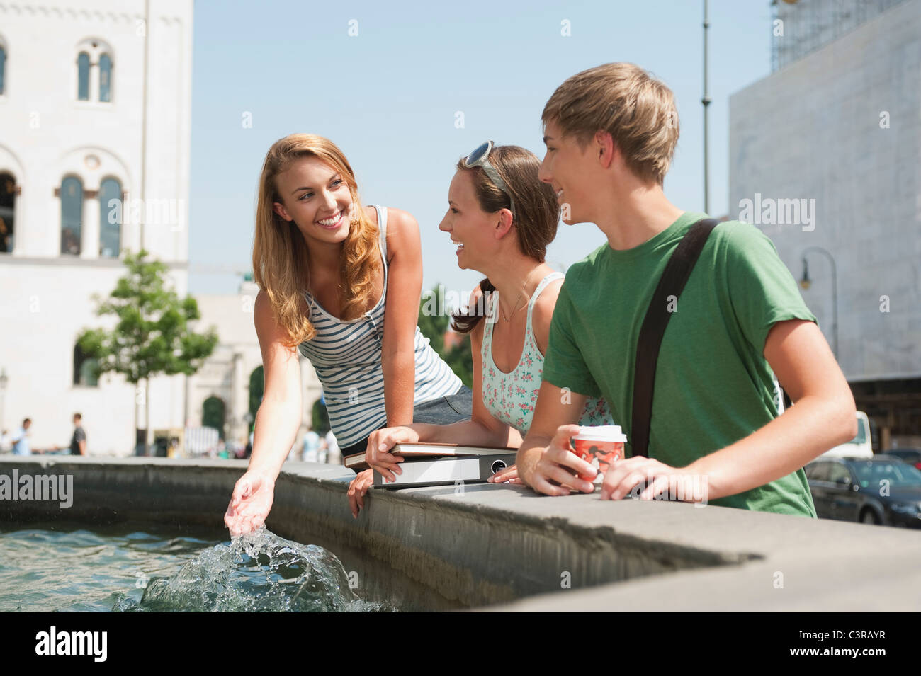 Allemagne, Munich, le jeune homme et les jeunes femmes à fontaine Banque D'Images
