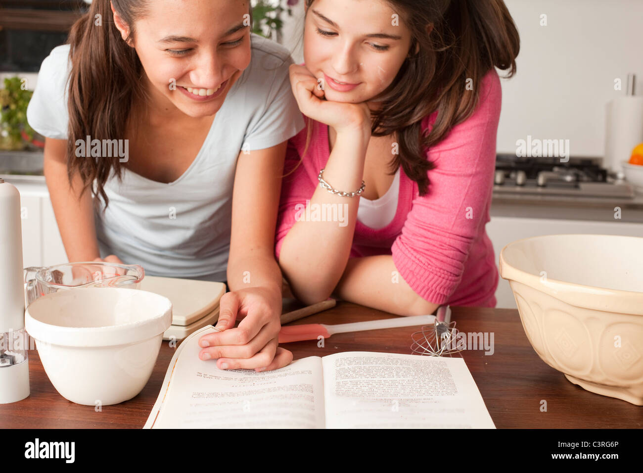 Teenage Girls looking at fiche dans la cuisine Banque D'Images