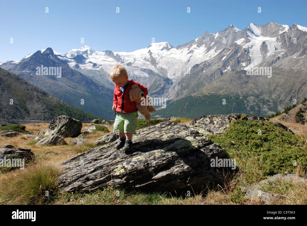 Un jeune garçon s'amusant à jouer sur les rochers à Kreuzboden, Saas Grund, Suisse. Banque D'Images