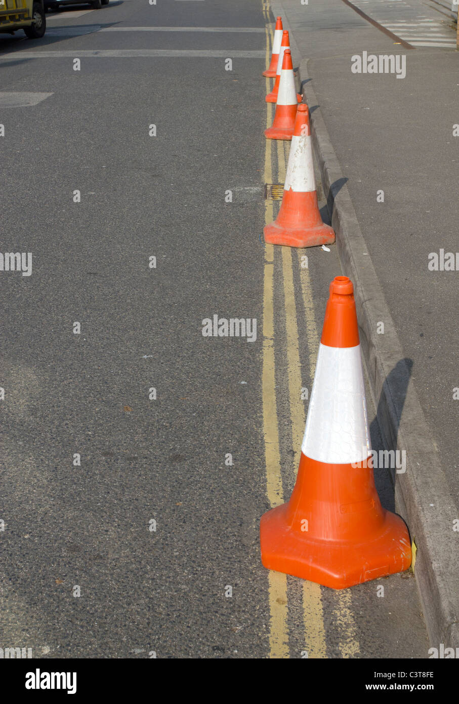 Une rangée de 5 cônes de signalisation de police sur double lignes jaunes. Banque D'Images