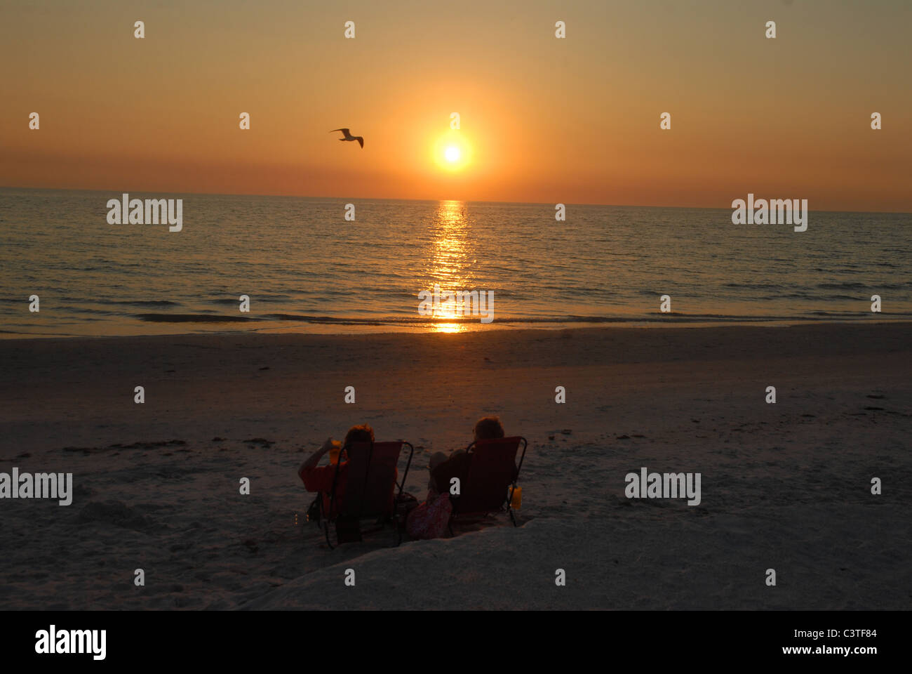 Le soleil se couche comme deux personnes regarder le coucher de soleil St Pete Beach, en Floride. Banque D'Images