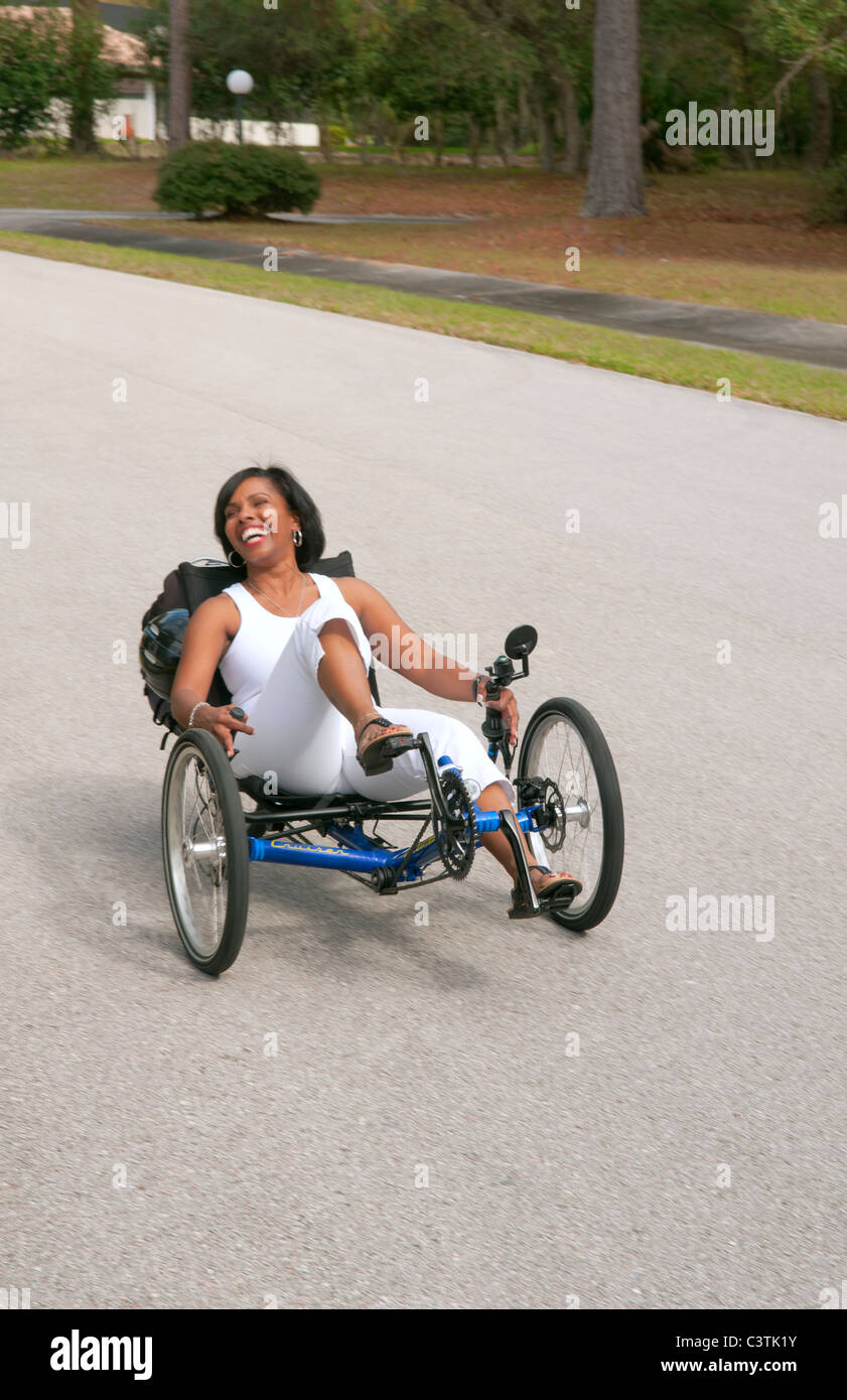 Femme noire ayant du plaisir de conduire le nouveau green machine appelée Terre un Trike tricycle couchés sur la route pour l'excitation autour de Banque D'Images