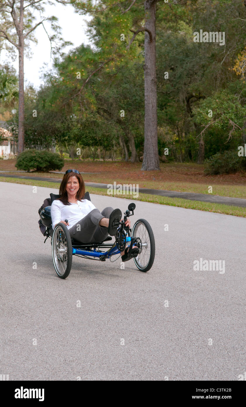 Femme ayant du plaisir de conduire le nouveau green machine appelée Terre un Trike tricycle couchés sur la route pour l'excitation autour de Banque D'Images