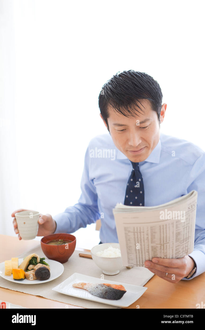 Petit déjeuner et businessman Having Reading Newspaper Banque D'Images
