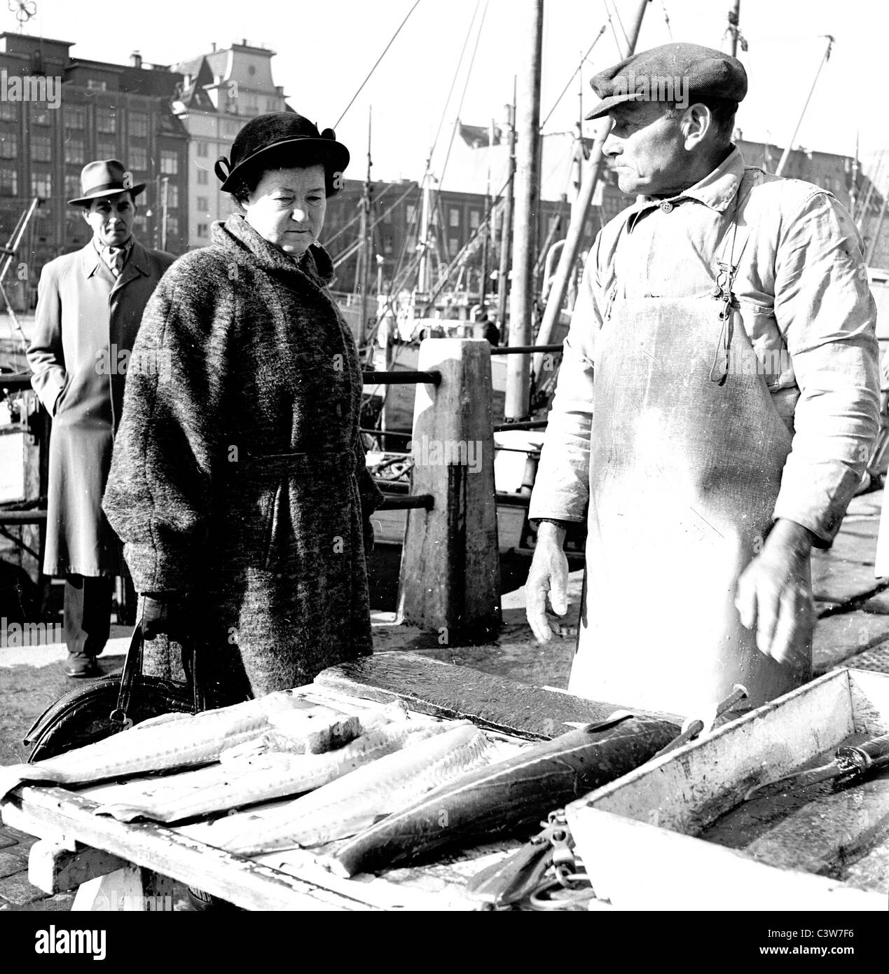 Années 1950. Dans ce tableau historique par J Allan paiement nous voyons une dame regardant les poissons disponibles sur le marché, Bergen en Norvège. Banque D'Images