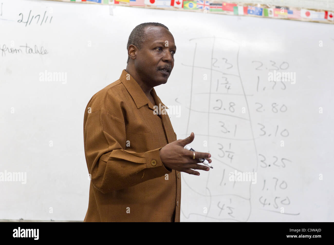 Professeur de mathématiques de mâle afro-américain parle à classe en face de tableau blanc avec des fractions d'inscrit à l'Académie Rapoport Banque D'Images