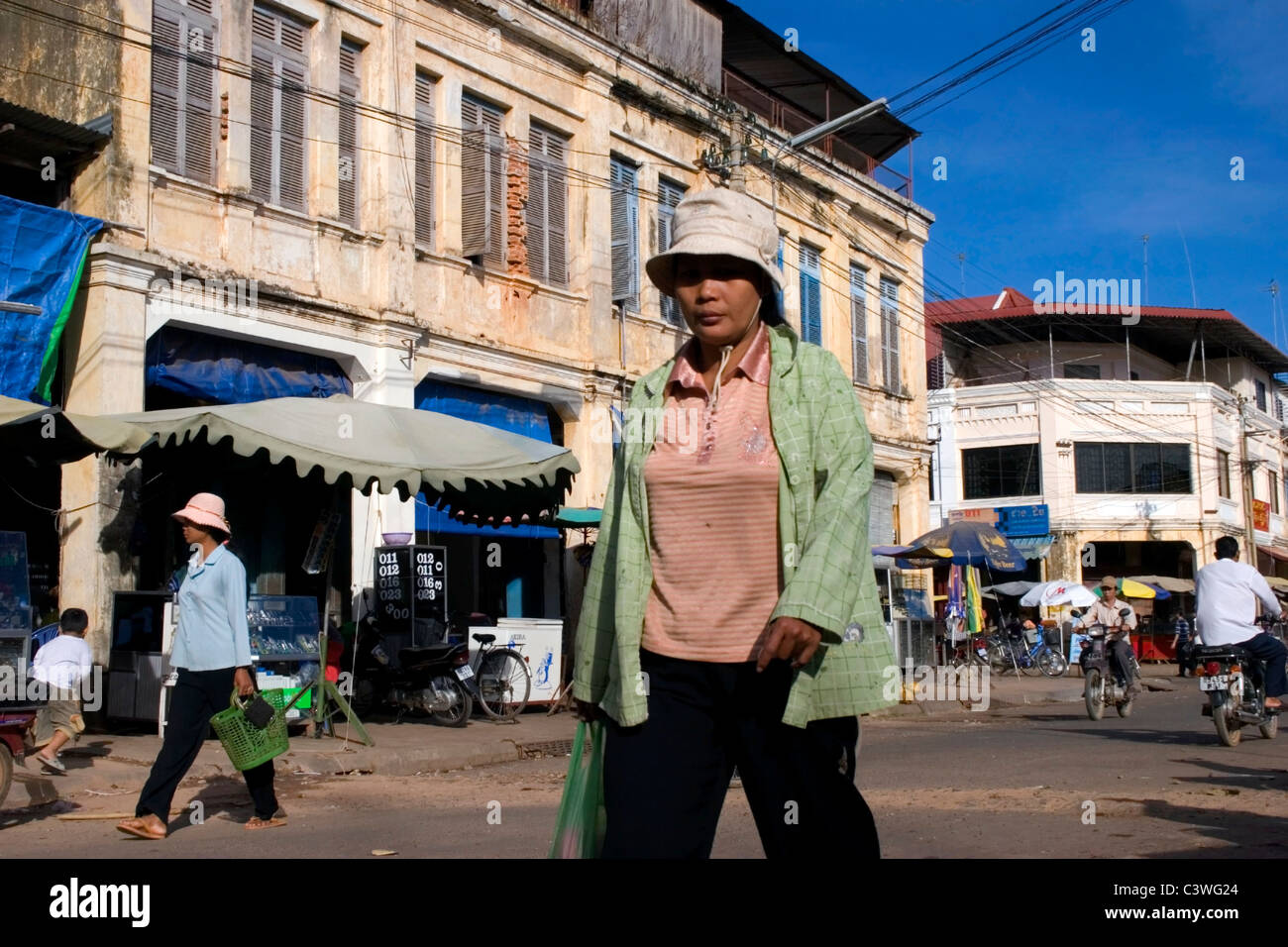 Une asiatique est passé à pied d'un bâtiment colonial délabré dans une rue de Kratie, rural au Cambodge. Banque D'Images