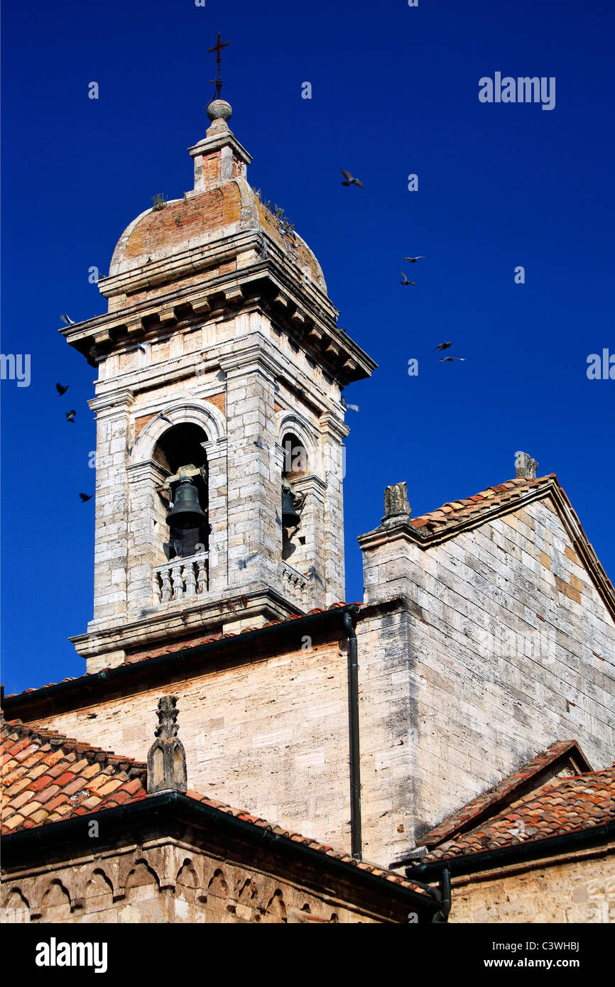 Un troupeau de pigeons voler du clocher de l'église collégiale des saints Quiricus & Julietta à San Quirico d'Orcia, Italie Banque D'Images