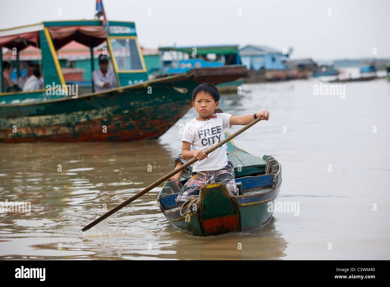 Jeune garçon cambodgien paddling son bateau en bois sur le lac Tonle Sap, au sud de Siem Reap, Cambodge Banque D'Images