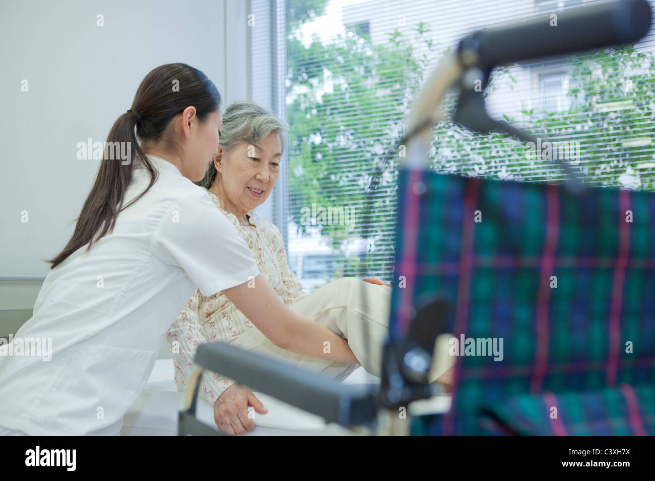 Levage infirmière senior woman pour fauteuil roulant du bed, Kanagawa Prefecture, Honshu, Japan Banque D'Images