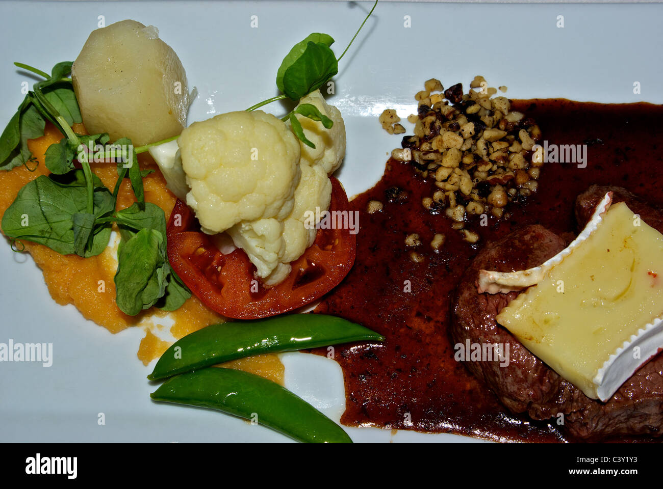 Bifteck de faux-filet grillé avec des tranches de fromage brie en sauce légumes vapeur mixte réduction plat principal Banque D'Images