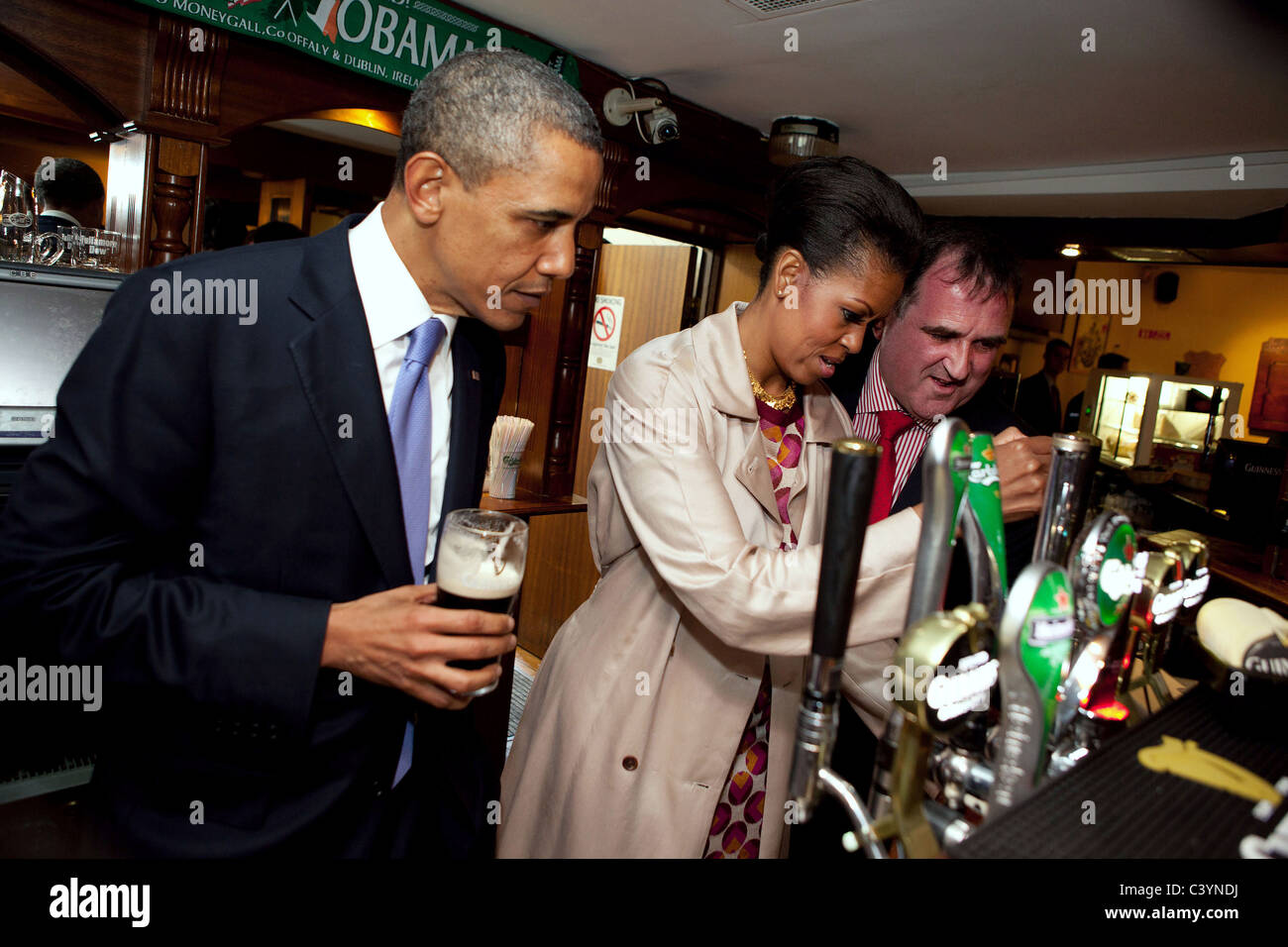 Le président Barack Obama observe alors que la Première Dame Michelle Obama dessine une pinte au pub Ollie Hayes' à Moneygall, l'Irlande, le 23 mai, 2011 Banque D'Images