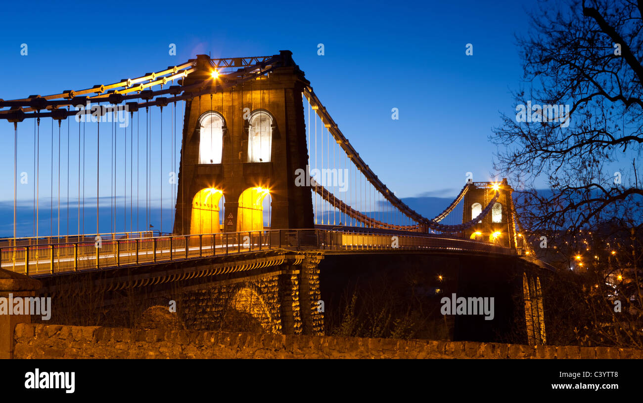 Illuminations en soirée sur le Pont Suspendu de Menai enjambant le détroit de Menai, Bangor, au nord du Pays de Galles, Royaume-Uni. Printemps (avril) 2011. Banque D'Images