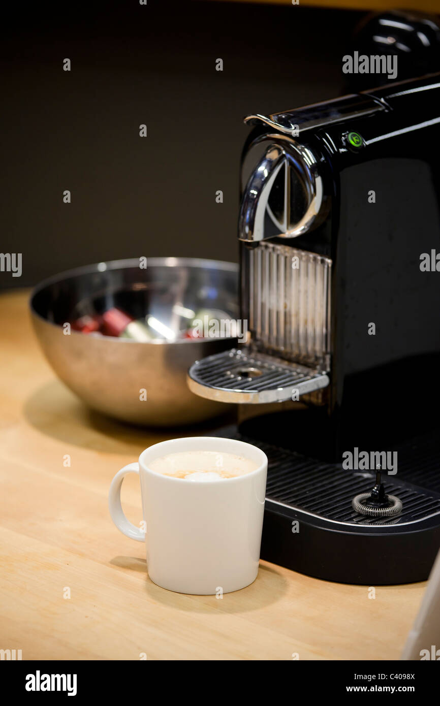 Close up of Nespresso machine à café espresso fraîchement nouveau brassage. Les capsules de café dans un bol en arrière-plan Banque D'Images