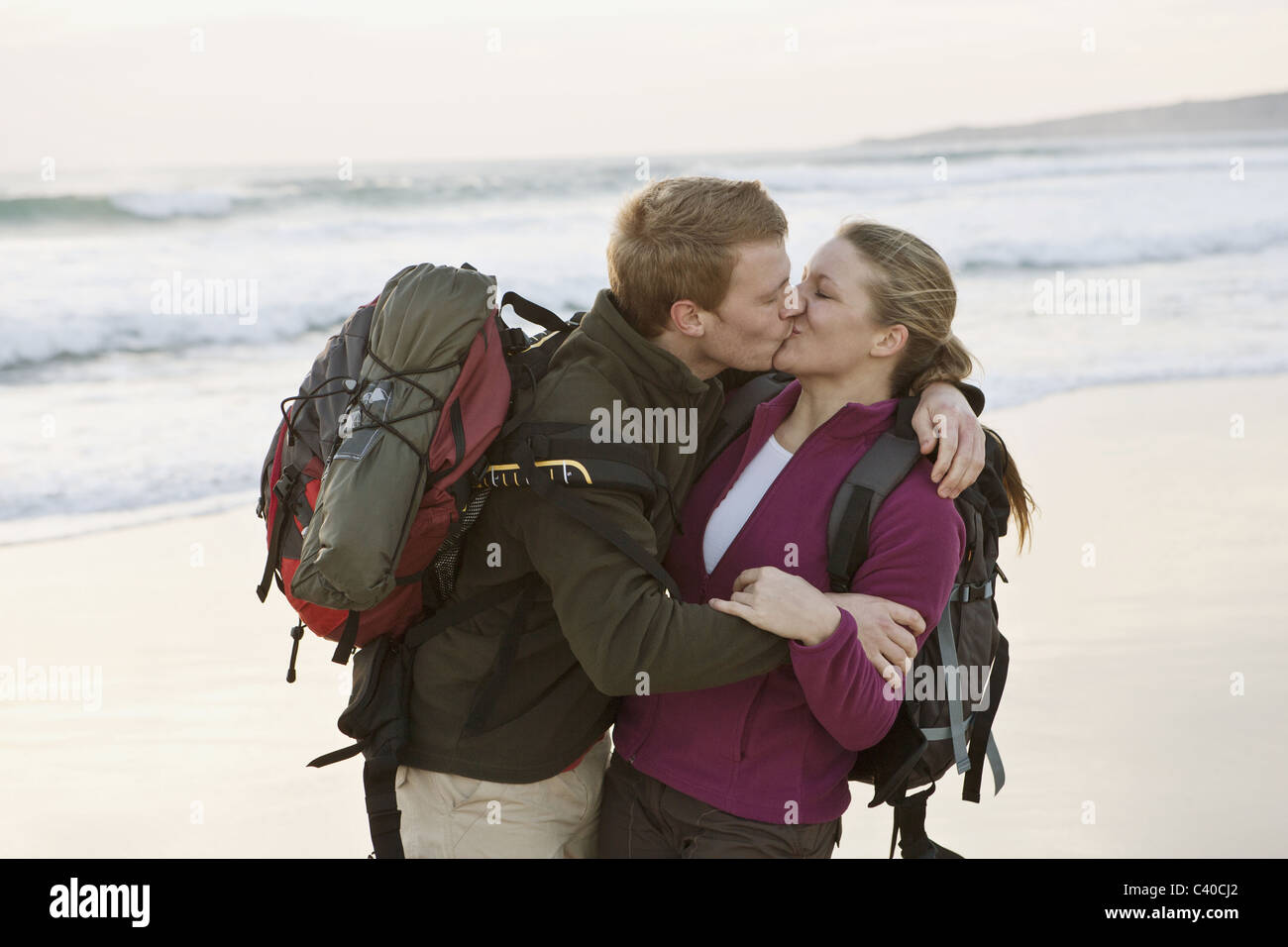 Backpacking couple kissing at beach Banque D'Images
