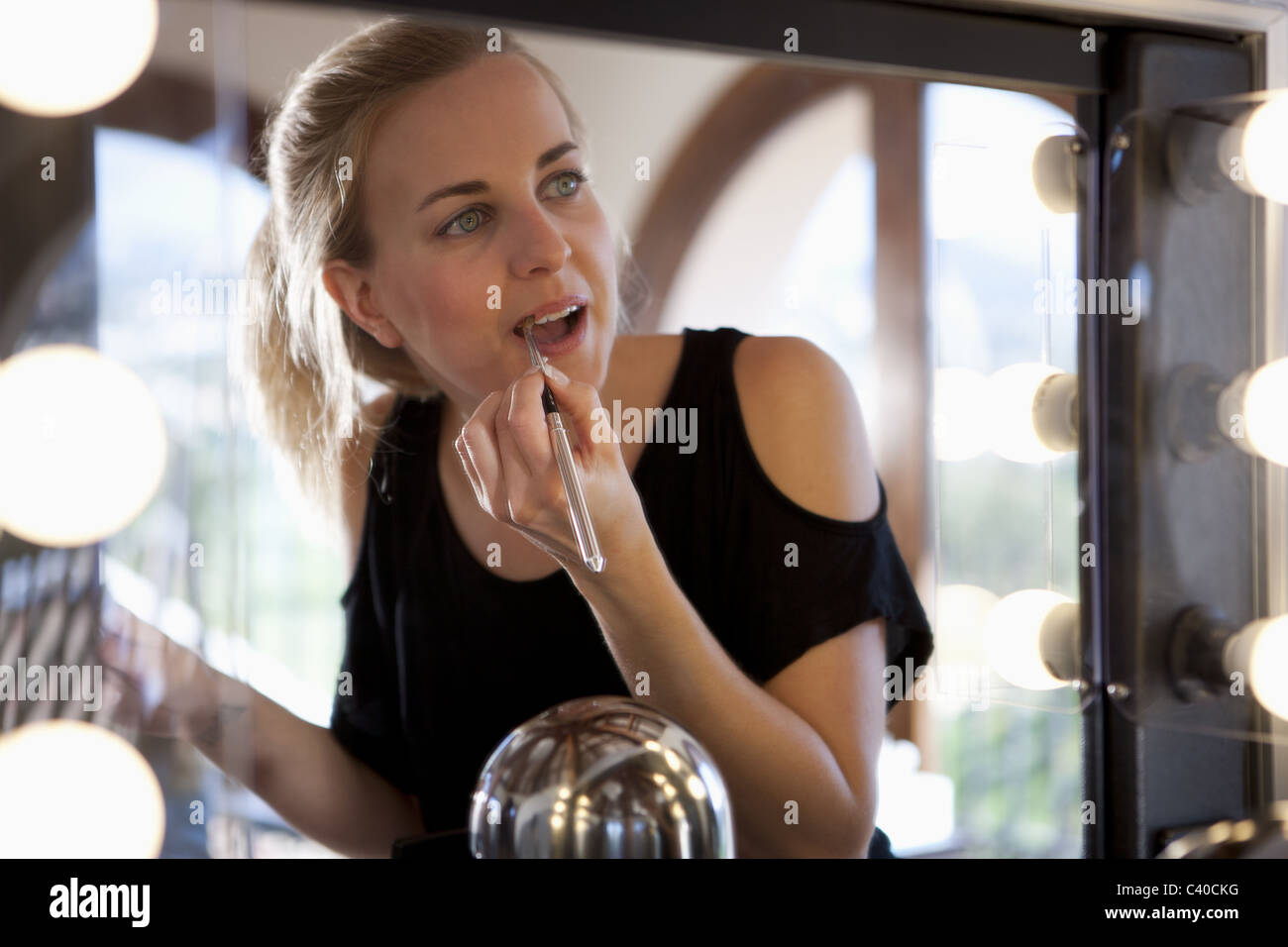 Woman applying lipstick à l'aide d'un miroir Banque D'Images