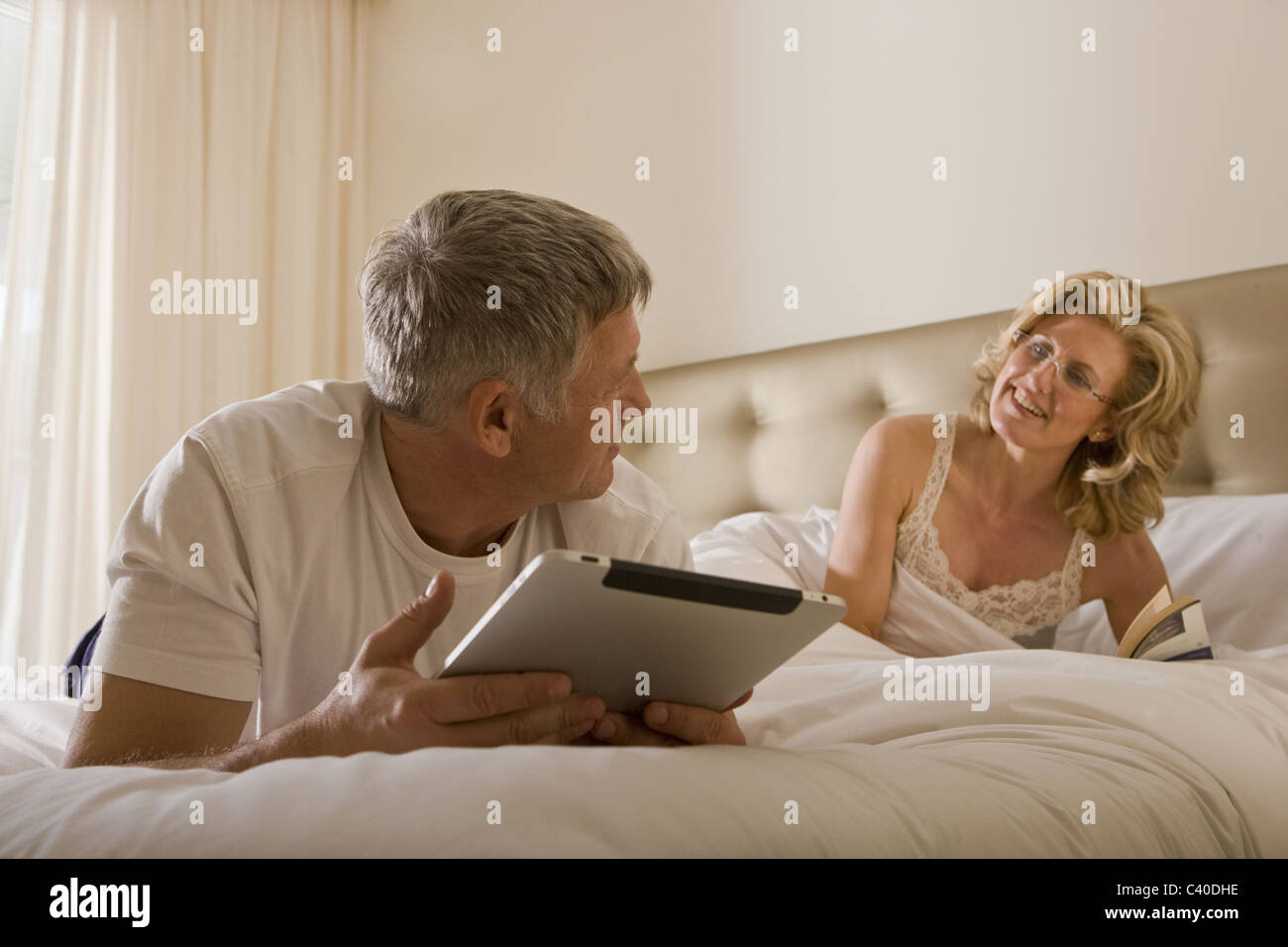 Man using tablet computer on bed Banque D'Images