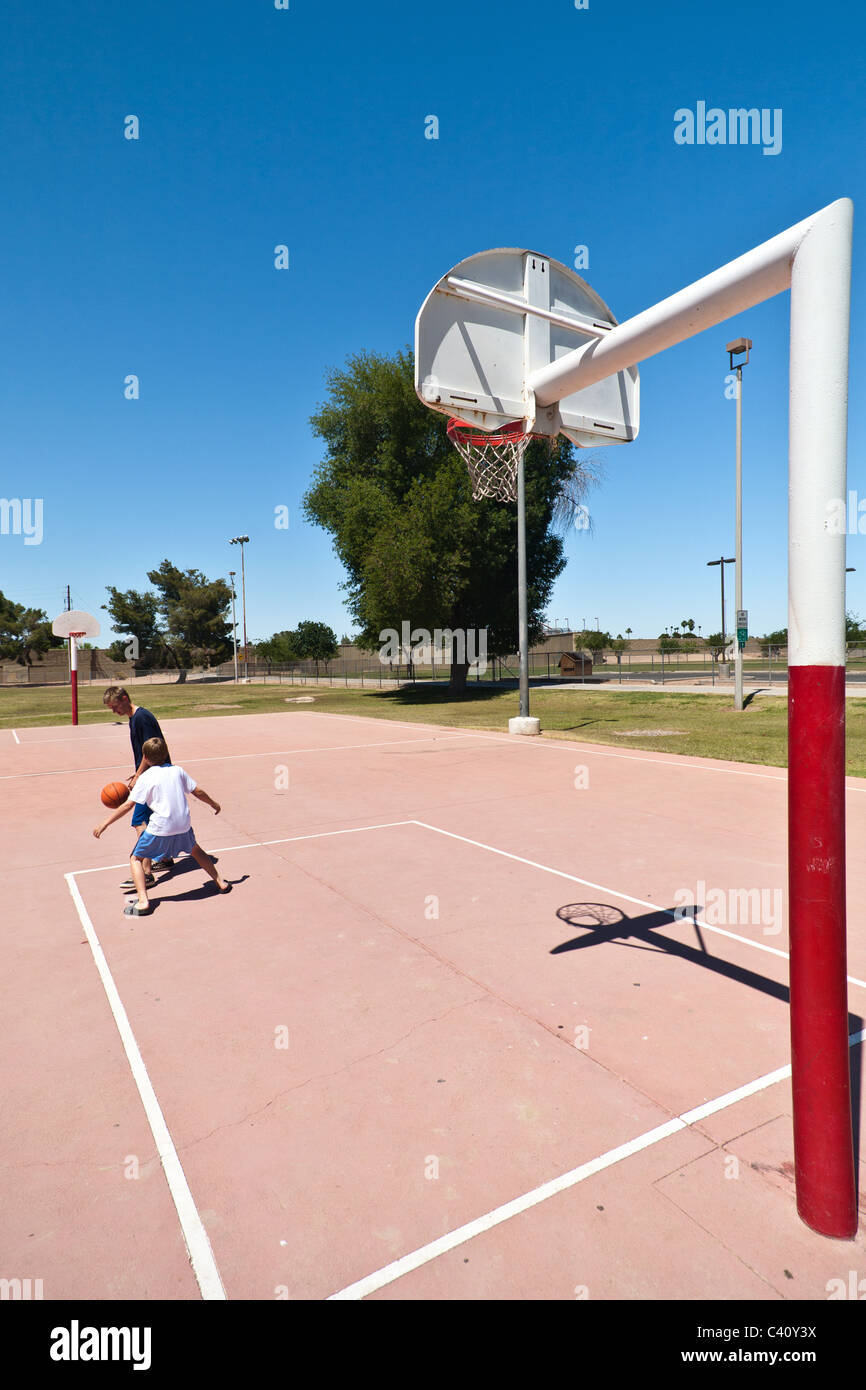 Garçons jouant au basket-ball à un parc de quartier en plein air Banque D'Images