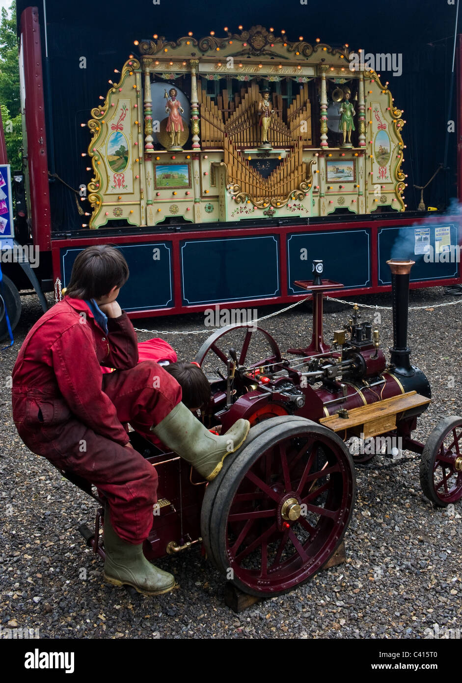 Un jeune garçon assis sur un moteur de traction miniature à un bain à vapeur vraiment. Banque D'Images