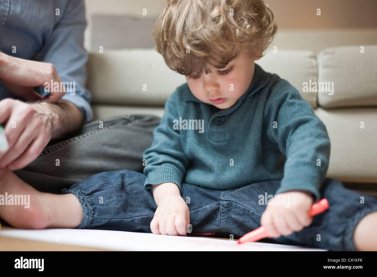 Tout-petit garçon assis sur le plancher avec le père, dessin sur papier Banque D'Images