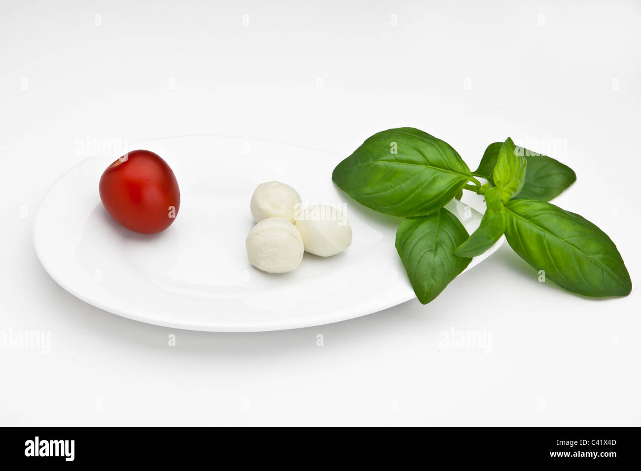 Boules de mozzarella avec tomates cerises sur une plaque blanche Banque D'Images