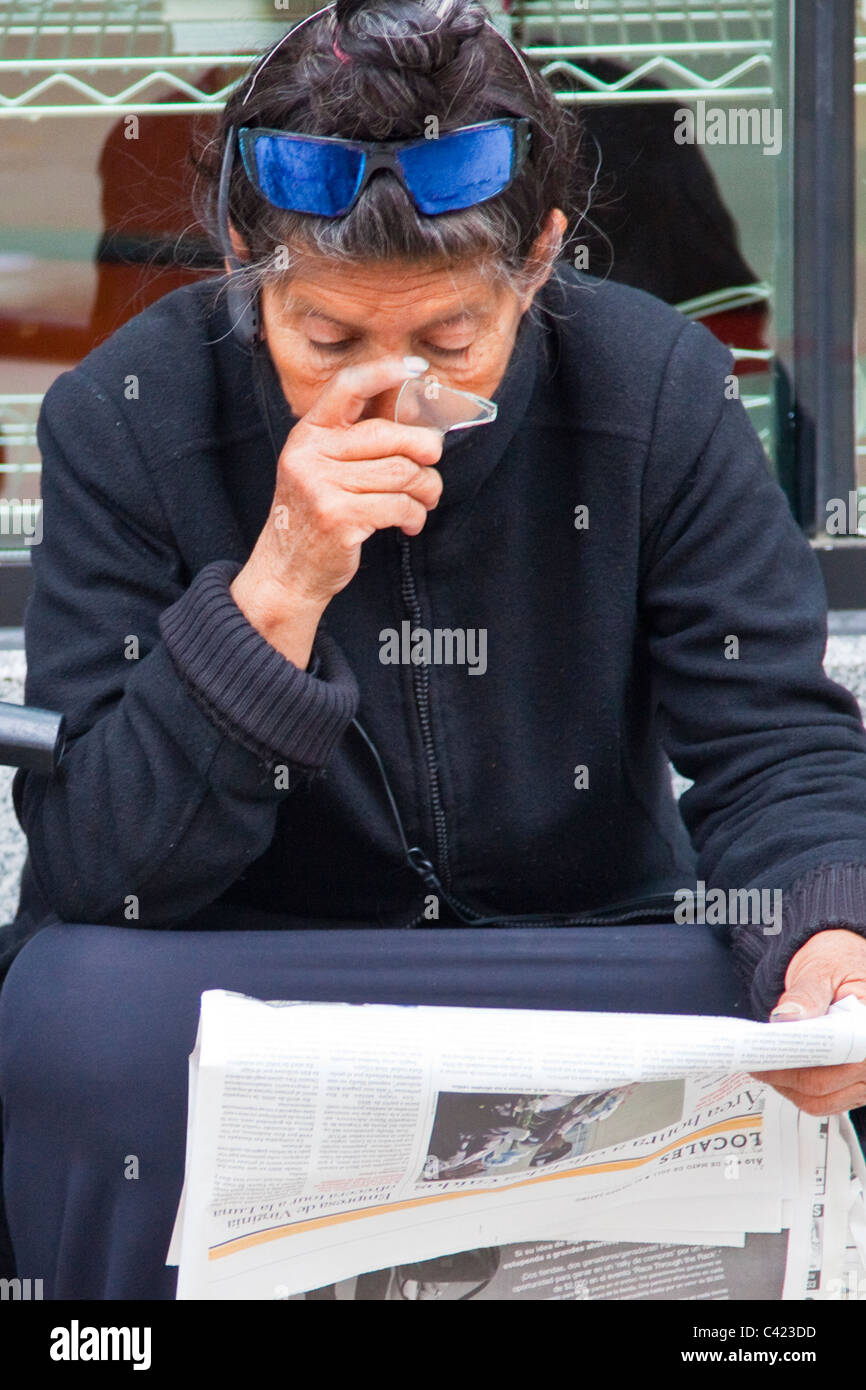 Femme sans-abri à l'aide d'un bas d'une bouteille cassée pour lire le journal, Washington DC Banque D'Images
