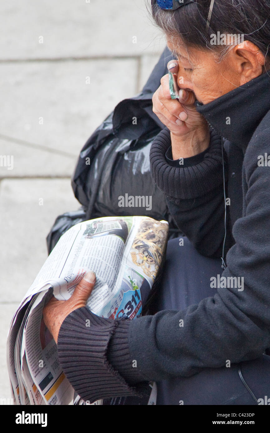 Femme sans-abri à l'aide d'un bas d'une bouteille cassée pour lire le journal, Washington DC Banque D'Images