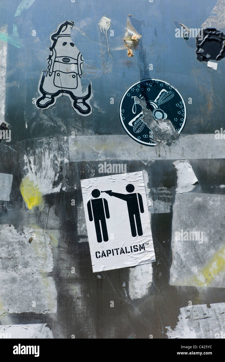 Sticker montrant un pictogramme avec deux fils par l'un pointant un pistolet a la tête d'autres avec le sous-titre le capitalisme TM Banque D'Images
