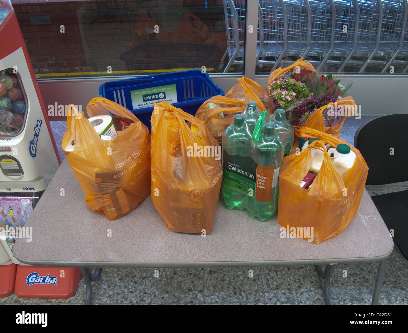 L'épicerie et des fleurs dans des sacs de supermarché sur une table dans le magasin Banque D'Images