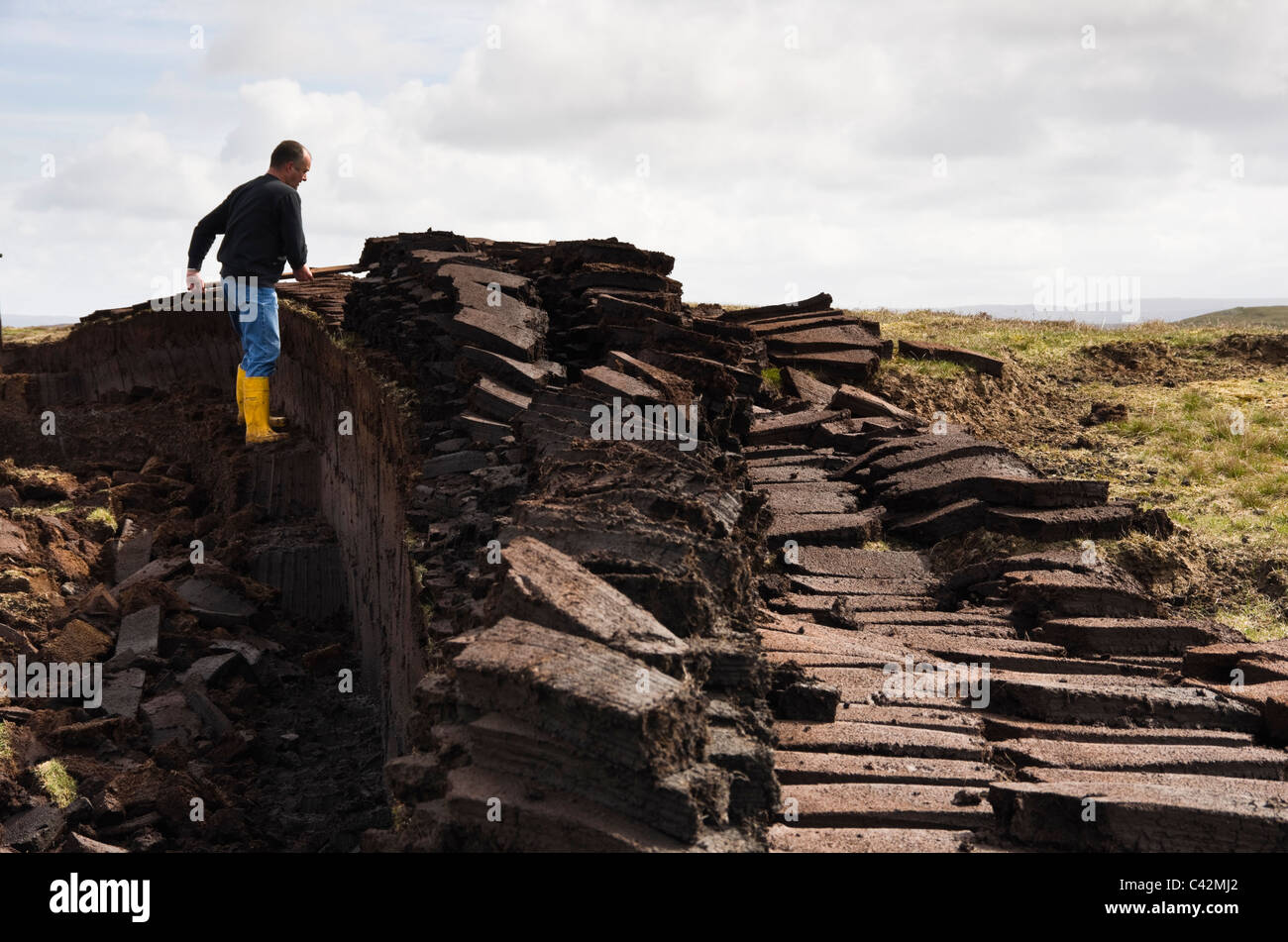 Les Îles Shetland, Écosse, Royaume-Uni, Europe. Coupe homme pour des blocs de tourbe combustible traditionnel Banque D'Images