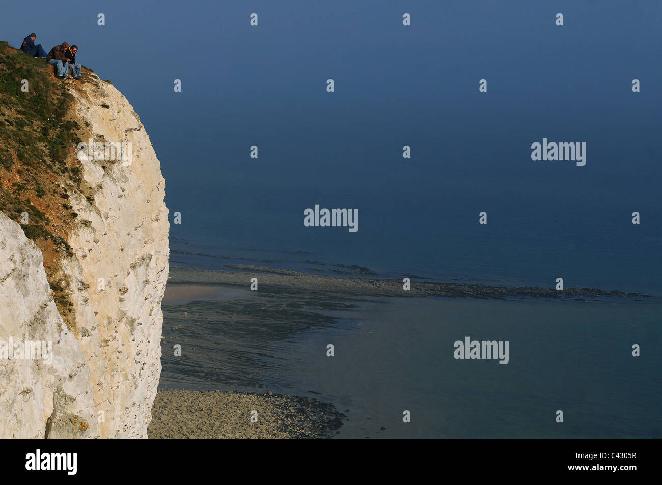 Un groupe d'amis s'asseoir près du bord des falaises de Beachy Head, East Sussex Banque D'Images