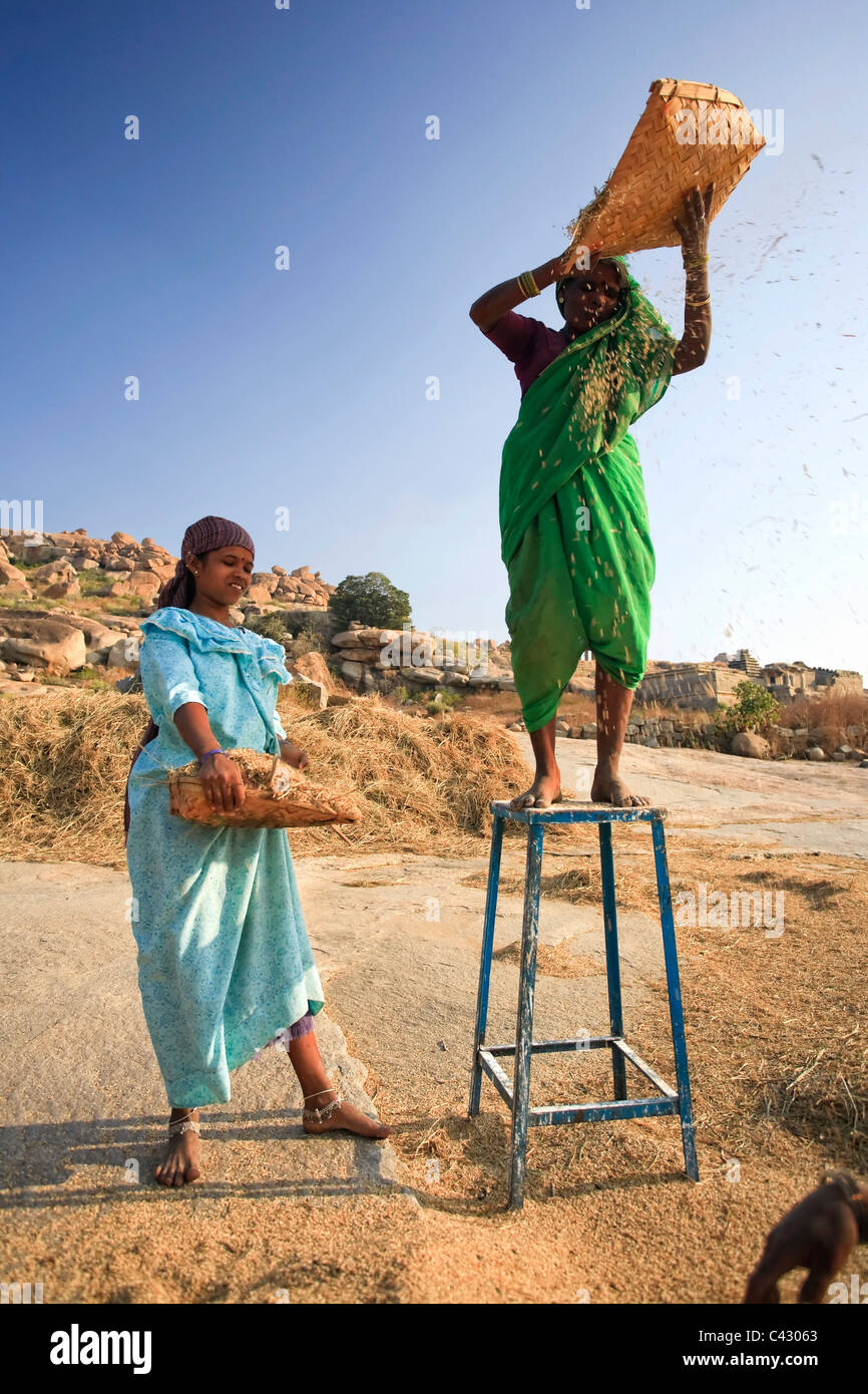 Les femmes le tamisage du riz, Hampi, Karnataka, Inde Banque D'Images