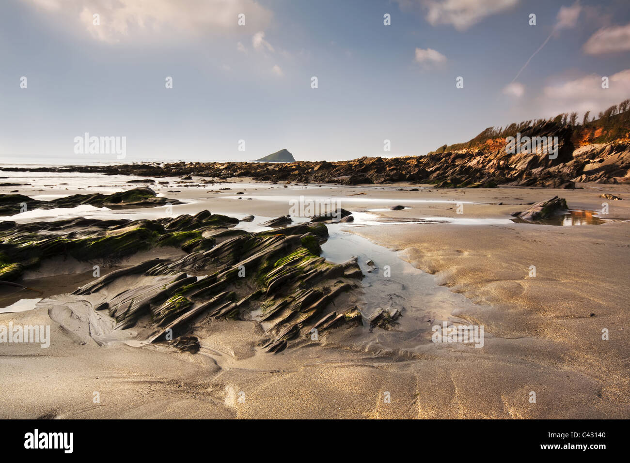 Tôt le matin voir de Wembury beach rocks menant vers la mer avec la grande Mewstone assis sur l'horizon Banque D'Images